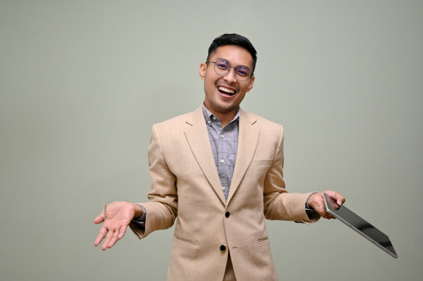 兴高采烈的亚洲商人拿着平板电脑，张开手掌，看着镜头图片下载