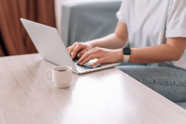 一位女士在桌子上用笔记本电脑工作，还有一杯咖啡图片下载