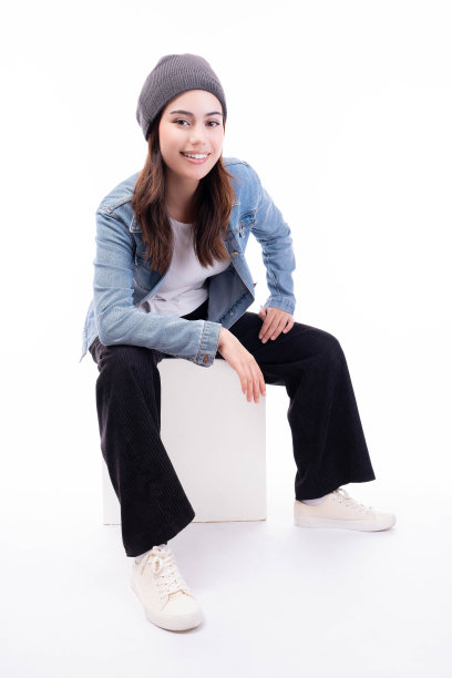 快乐的青少年年轻酷女子戴无檐帽酷潮女大学生看着相机笑得很开心孤立在白色背景漂亮的女孩穿牛仔夹克坐在立方体椅子上图片下载