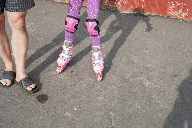 一个男人牵着一个正在学滑旱冰的女孩的手图片下载