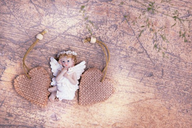 特写两颗心和小天使那破旧的米黄色修复墙或地板。婚礼贺卡，生日贺卡，母亲节贺卡，波西米亚风格贺卡图片下载