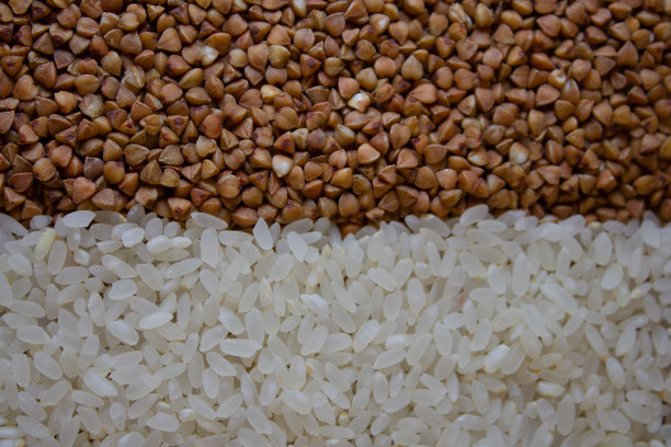 背景是荞麦和大米的混合物。一边是荞麦粒，另一边是米粒。背景来自一半的荞麦和大米。谷物概念背景。图片下载