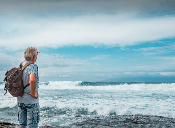 在海滩上享受幸福和自由的高级男子-背着背包的男性在大自然中旅行，看着水面上的地平线-健康的生活方式，退休和旅行理念图片下载