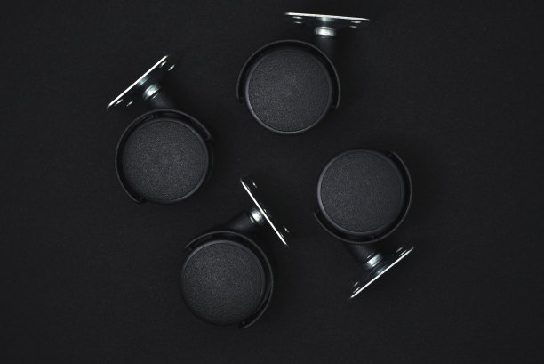 黑色背景上的黑色塑料家具滚轮。图片下载