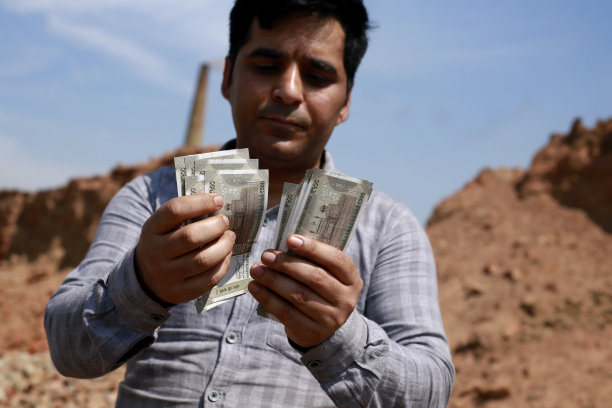 一名印度男子站在砖厂附近数着500卢比钞票——月薪、生意、利润、印度货币图片下载