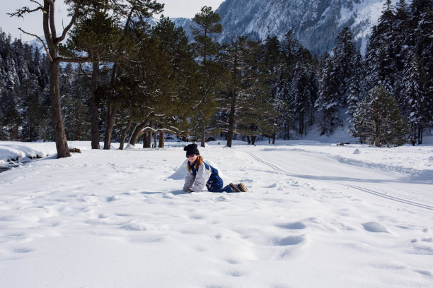 可爱的微笑的年轻女孩玩在一个美丽的雪山景观图片下载