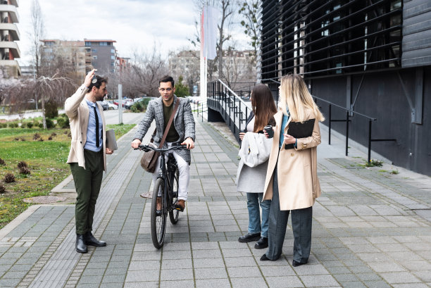 年轻的商人骑着自行车穿过三个赶着上班的商人。一个骑自行车的人因为去办公室开员工会议迟到，从愤怒的人群身边经过。图片下载