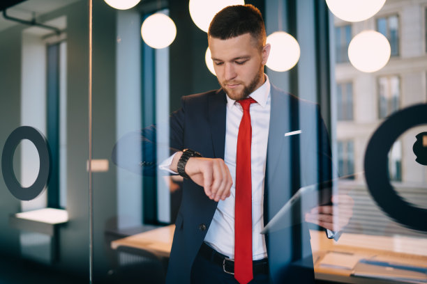 严肃的男性办公室职员看手表的时间图片下载