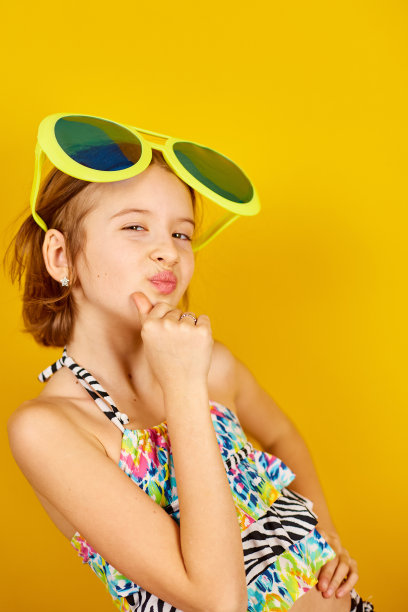 微笑的少年女孩在泳装和大太阳镜摆姿势图片下载