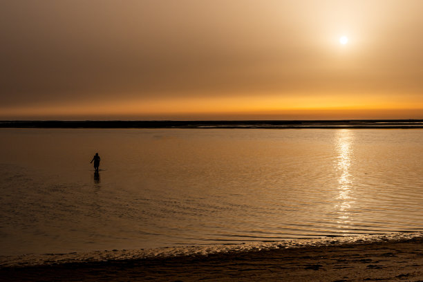 日落时分走在海滩上的女人剪影。水平照片与复制空间。图片下载