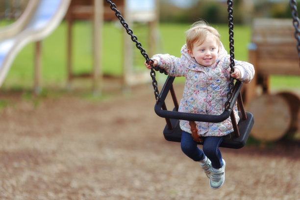 快乐的笑2岁的女孩享受在游乐公园的秋千图片下载
