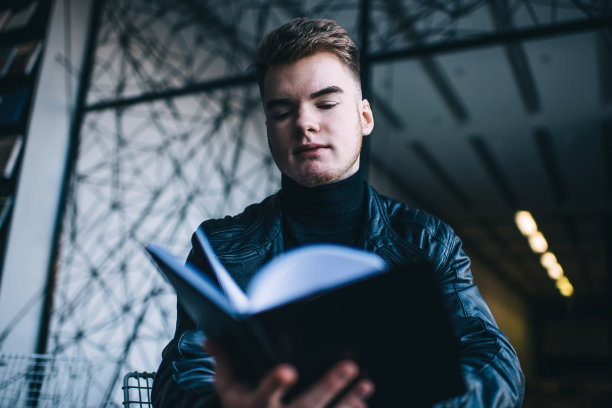 一名男子正在翻阅黑色封面的书图片下载