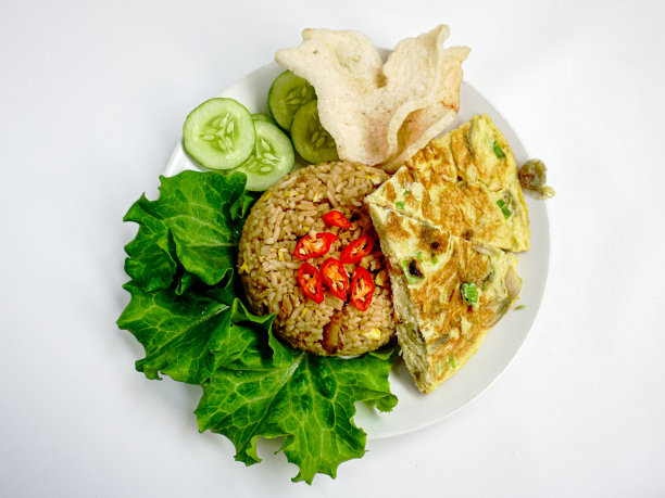 炒饭或炒饭配鸡蛋、虾饼、生菜和黄瓜片。炒饭是一道印尼菜。巴厘岛的食物。亚洲餐。俯视图图片下载