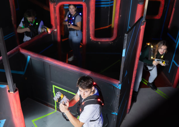 激光枪战玩家积极微笑的男孩和女孩在黑暗的激光枪战房间里玩。从高处俯瞰图片下载
