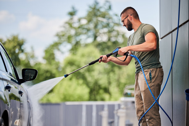 裁剪图像的人清洗他的车在自助洗车与高压水射流。图片下载