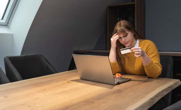 支付过程中被窃取的信息。困惑女子手持塑料银行信用卡无法进入开户网站。失望的女客户在网上购物时遇到诈骗图片下载