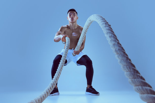 年轻肌肉男子训练的肖像，在霓虹灯蓝色背景上孤立地拉绳子图片下载