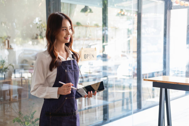 一个女人的肖像，一个咖啡店老板微笑着美丽地开了一家咖啡店，这是她自己的生意，小企业的概念。图片下载