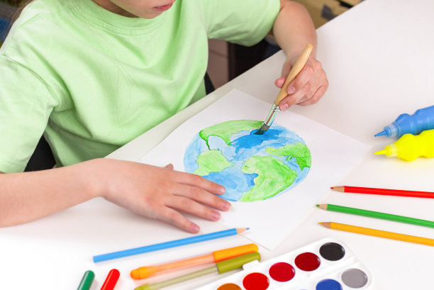 一个孩子用颜料和画笔画一个地球仪。图片下载