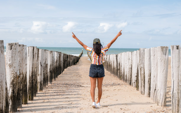 度假期间，快乐的女性在海滩上举起双手，在荷兰Domburg Zeeland的海滩上撑杆图片下载
