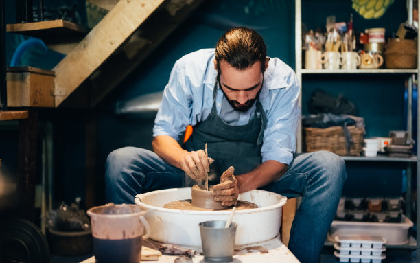 陶工工匠在车间的陶工轮圈上制作陶土壶图片下载