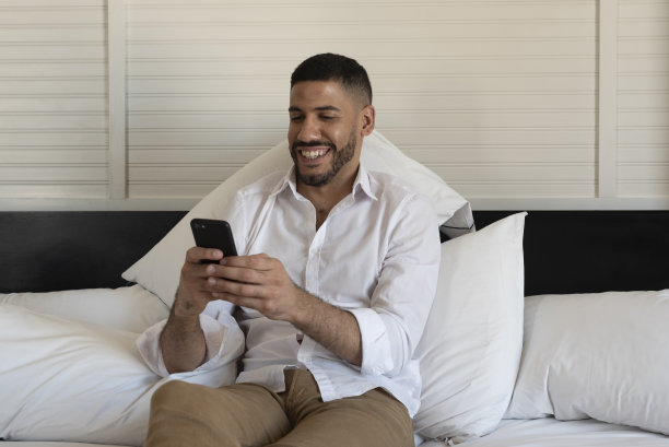 商人躺在酒店的床上使用智能手机图片下载