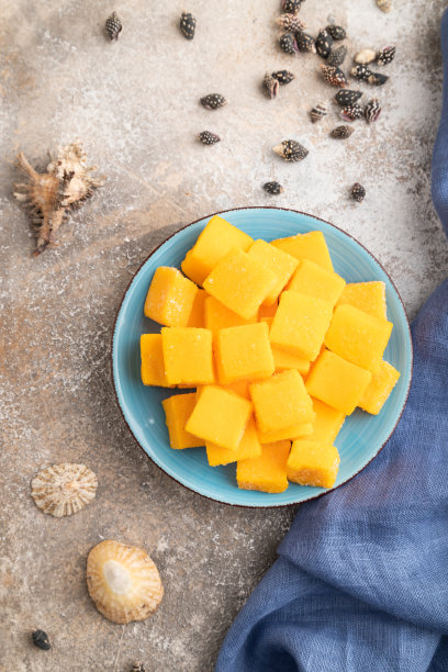 芒果干放在棕色混凝土的蓝色盘子上，俯视图。图片下载