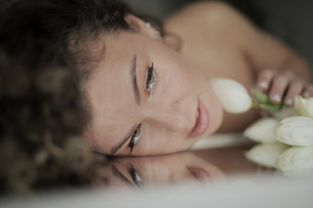 一位美丽的年轻女子捧着一束郁金香躺在镜子上图片下载