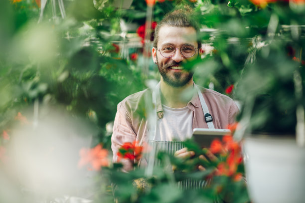 在温室里工作的园丁正在使用平板电脑图片下载