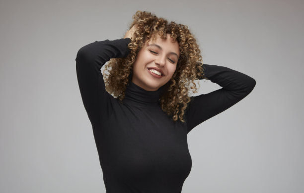 手持卷发的快乐年轻女子肖像图片下载