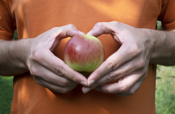 男人的手拿着苹果，在苹果上做心形。健康生活理念图片下载