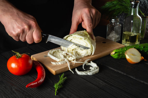 厨师手切新鲜的白菜和蔬菜做沙拉。餐厅或咖啡馆的烹饪和概念图片下载