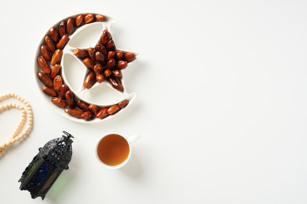 斋月卡里姆概念。白桌上放着干枣，阿拉伯灯笼，一杯茶，念珠。图片下载