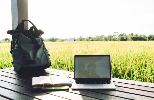 有选择性地关注现代笔记本电脑和教育教科书，用于在印度尼西亚远程工作期间进行新闻研究，旅行背包和上网本用于数字游牧生活方式图片下载
