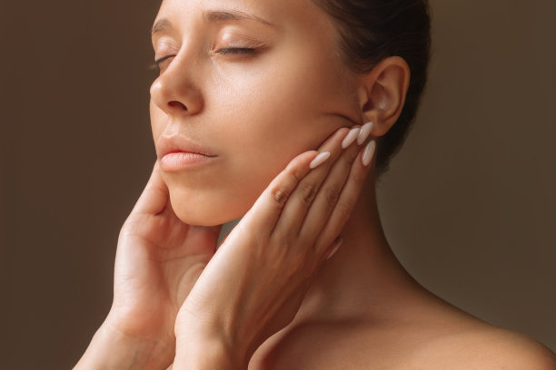 年轻女子触摸皮肤与手按摩她的脸。年轻化、拉皮、塑形图片下载