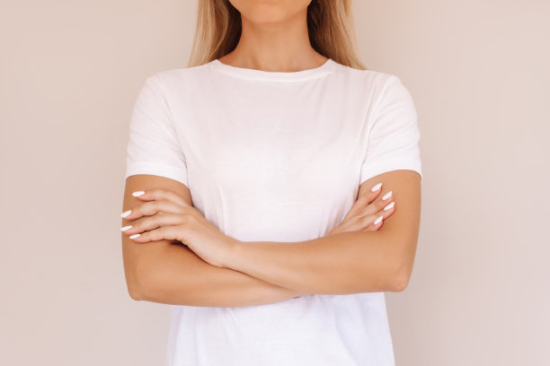 一个穿着白色t恤的年轻金发女子双臂交叉放在肚子上的短镜头图片下载