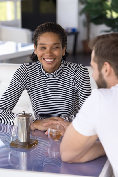 快乐美丽的年轻黑人女孩坐在咖啡馆的桌子上，图片下载
