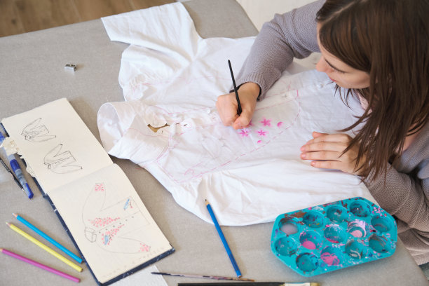 一个女人用丙烯酸颜料在衬衫上手绘设计的俯视图。图片下载