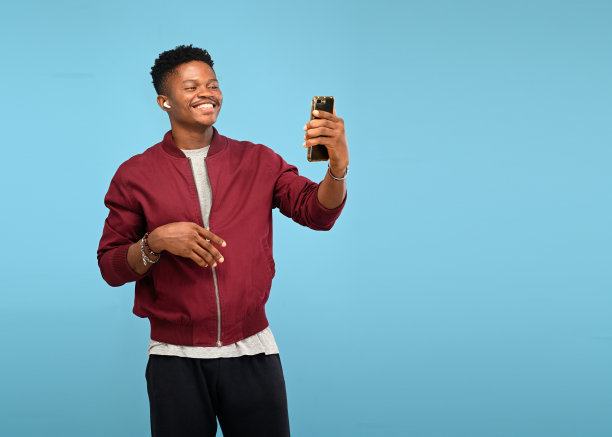 微笑的非洲黑人男子摆姿势用手机自拍图片下载