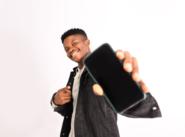 热情的运动员用手指着手机屏幕微笑。男士在便服展示智能手机应用程序，演示电话界面，白色背景图片下载