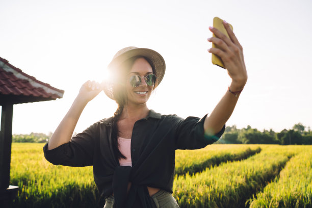 背光自拍摄影通过现代移动技术，繁荣的潮女孩在印度尼西亚的晴天拍摄视频视频使用数码智能手机小工具和滤镜应用图片下载