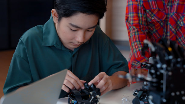 学生正在试着把他的手指放在手指环上的机械手，那是由人类创造的控制机械手的机械手，孩子正在试着学习使用机械手，一步步戴上手指手触摸系统。图片下载