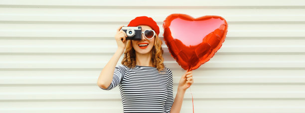 夏天的肖像快乐微笑的年轻女子与电影相机和红色心形气球戴贝雷帽在白色背景图片下载