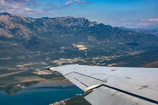 在群山背景下飞行的飞机的机翼图片下载