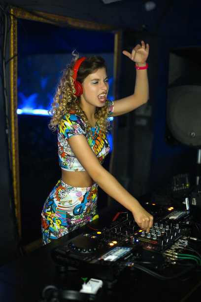 美丽积极的女孩DJ金发精力充沛的演奏和听音乐在夜总会，派对，在远程图片下载