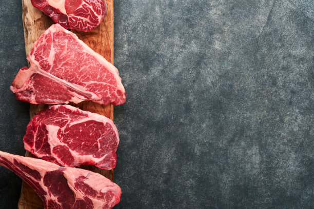 生牛排。各种新鲜的黑安格斯优质肉牛排t骨，纽约，Ribeye, Striploin，战斧砧板上的黑色或深色背景。各种经典牛排。前视图。图片下载