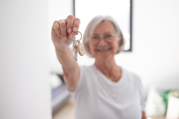 模糊微笑的女人拿着家里的钥匙。梦想之家。女性快乐的赢家买家租客新家庭公寓的租客，自豪的房主看着相机显示现代公寓的钥匙图片下载