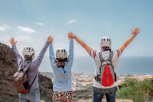 后景资深朋友背着背包在山上享受徒步旅行的日子-无忧无虑的登山游客举起手臂看着地平线，自由，成功的运动理念图片下载