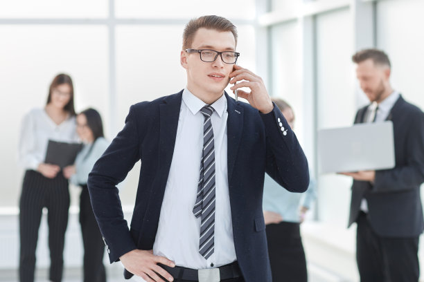 商人站在商务中心的大厅里用智能手机通话。图片下载