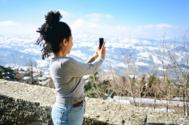 一名巴西妇女用电话拍摄风景优美的山脉。图片下载